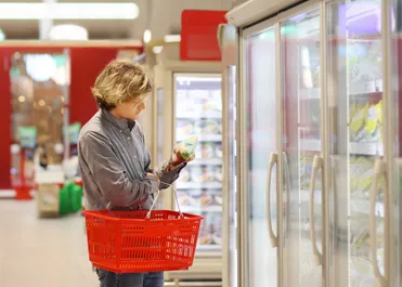 Man looking at frozen food in a grocery store freezer