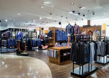 View of a men's retail store with suit jackets and ties hung on clothing racks