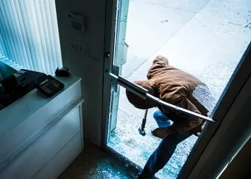 Person smashing a glass door and entering a building