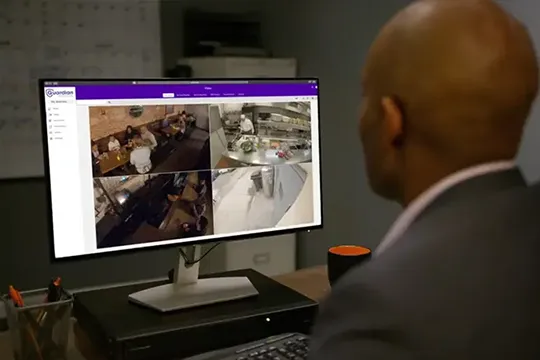 Man in a business office looking at security camera feeds