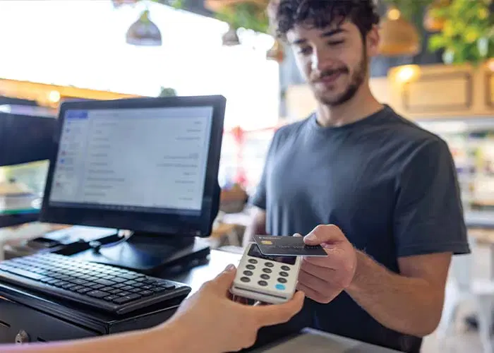 Clerk taking a customer payment on a cannabis dispensary sales floor.