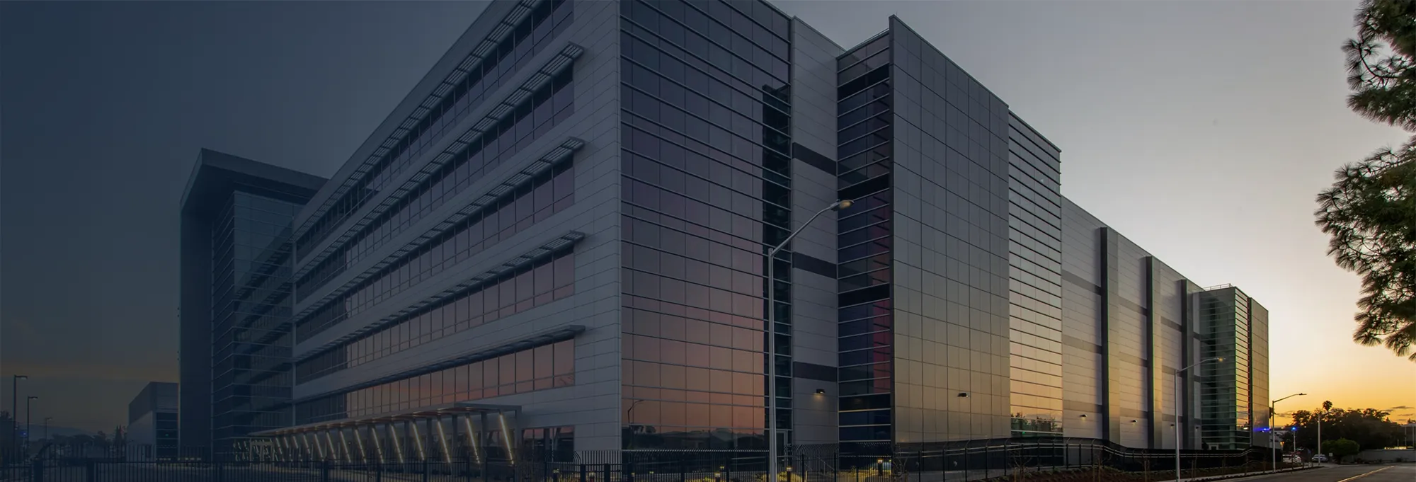 Photo of a large office building with the sun setting in the background.
