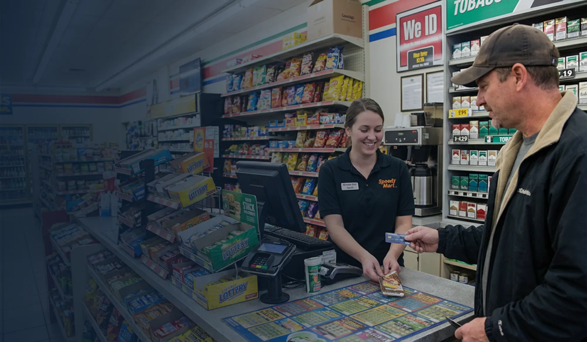 Convenience store associate assisting a customer at the counter.