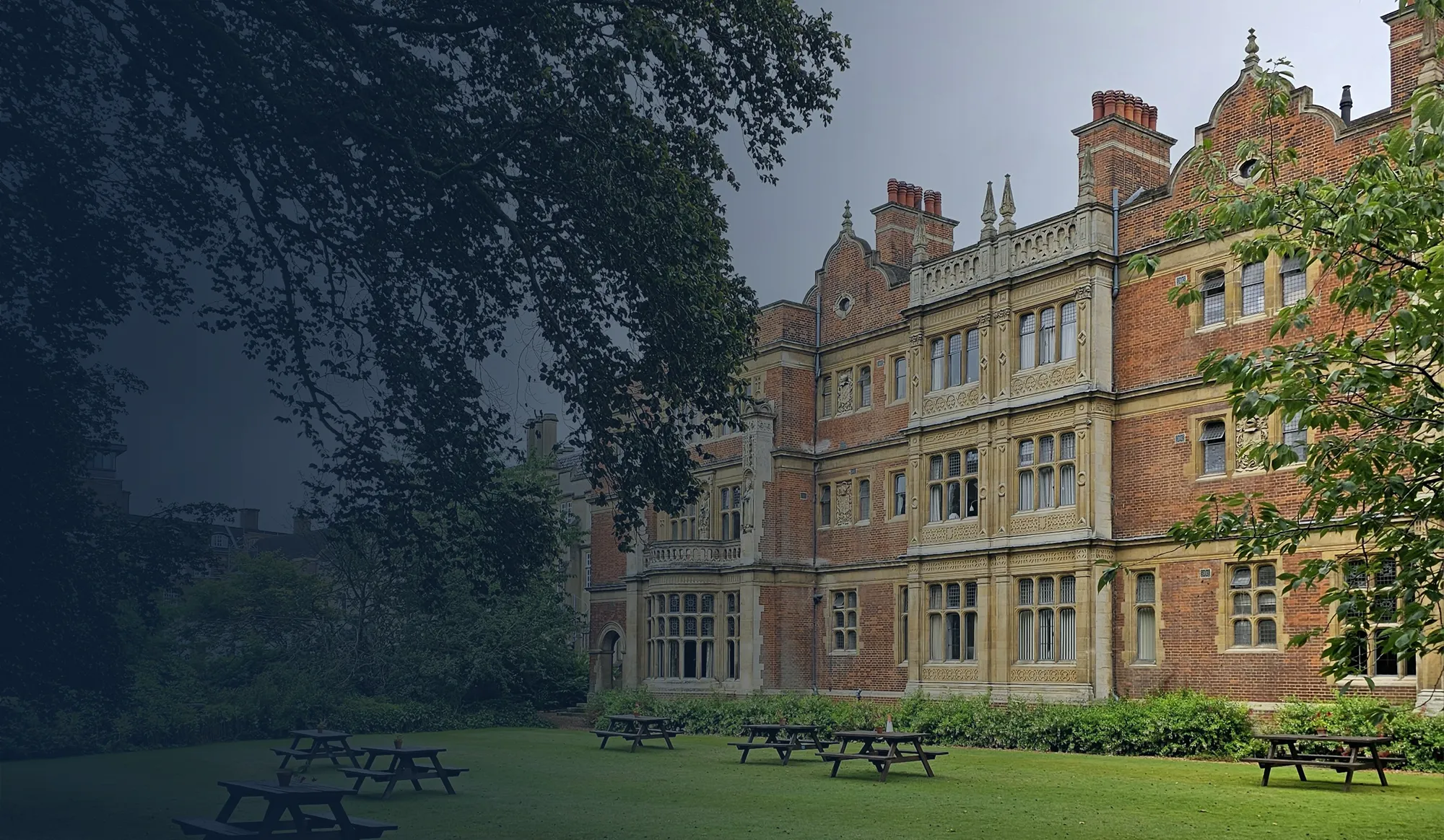 An historic college building with a sprawling lawn with picnic tables
