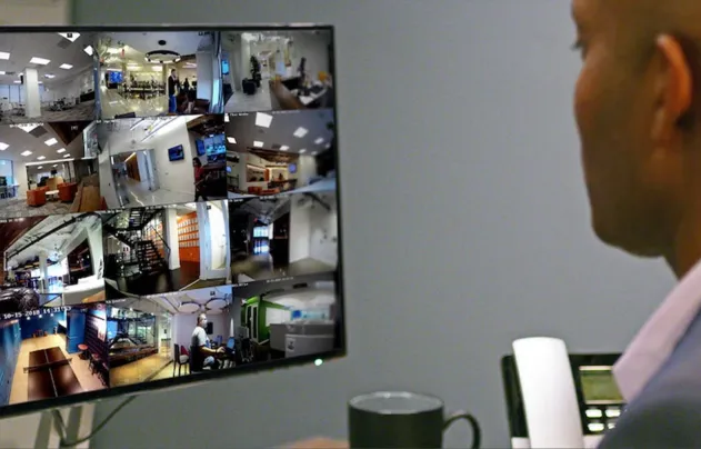 Man looking at a screen of security video feeds.