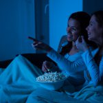 Image of two friends sharing popcorn and watching a movie together 