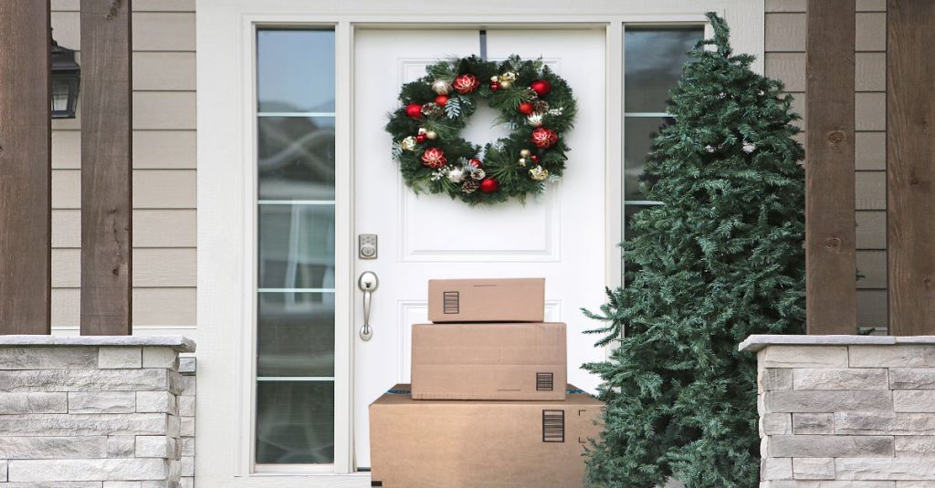 A holiday decorated porch with a stack of three delivery boxes