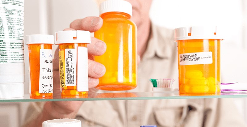 Man reaching for a medicine bottle in medicine cabinet