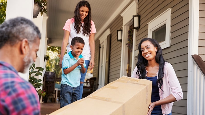 Family moving box up front porch steps