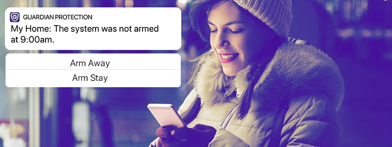 Woman checking phone for arming reminders from Guardian Protection app