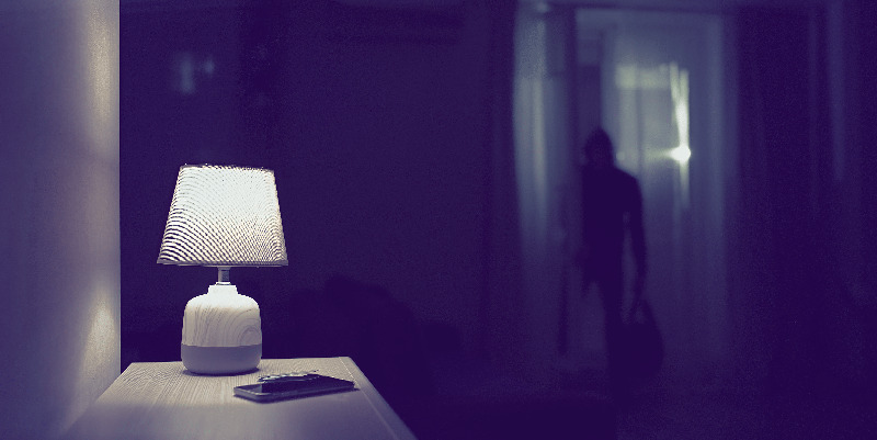 Silhouette of burglar standing in the doorway of a living room