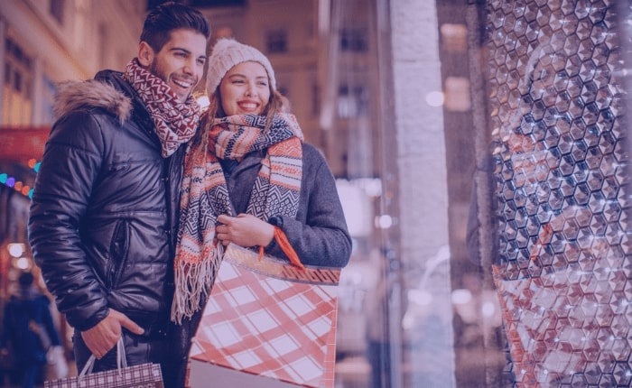 A couple looking in a store window while holiday shopping