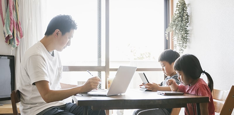 Father with two small children working remotely at kitchen table