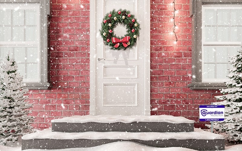 Snow covered porch with Christmas wreath on door and Guardian Protection sign in yard