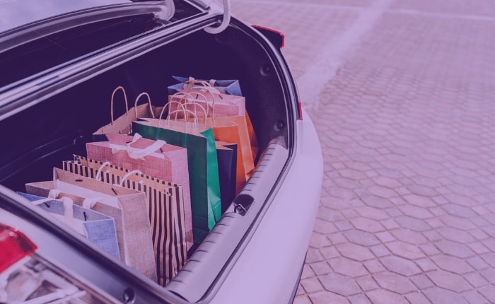 A car trunk open to show multiple holiday shopping bags