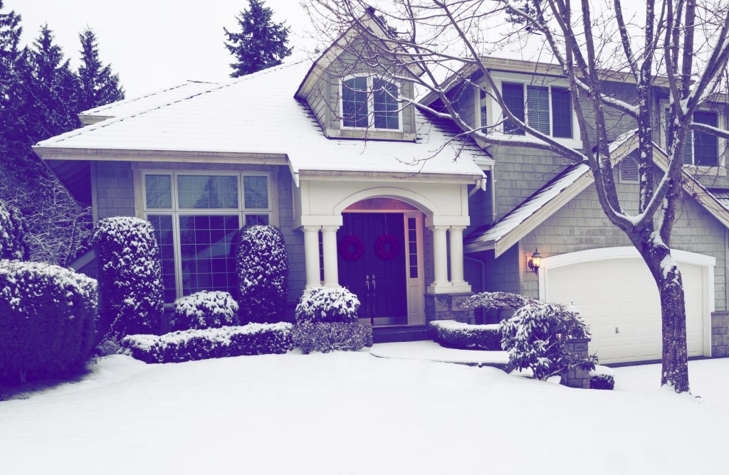 House with snow covered bushes and front lawn