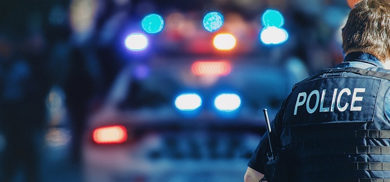 Police officer with patrol car in the background