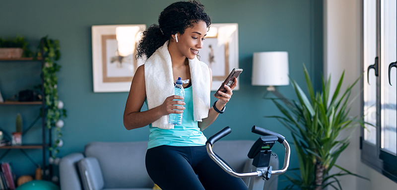 Woman checking her phone while working out on exercise bike