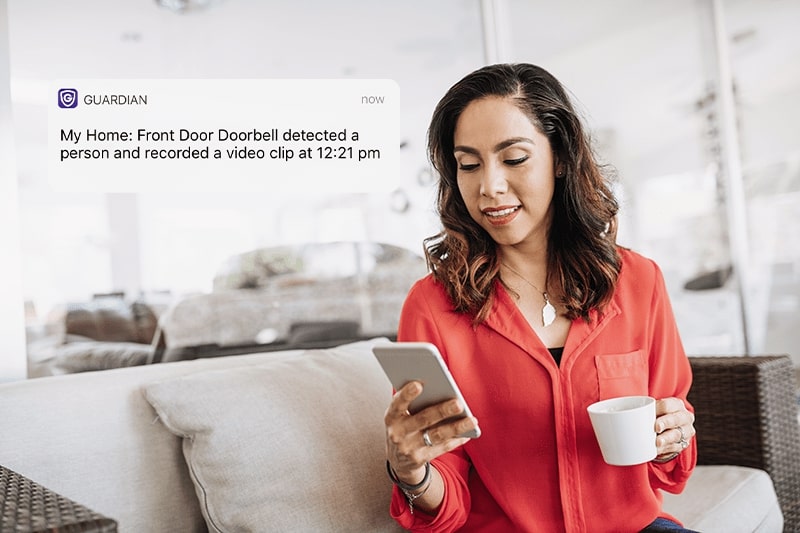 Female Guardian Protection customer checking an app notification on her smart phone.