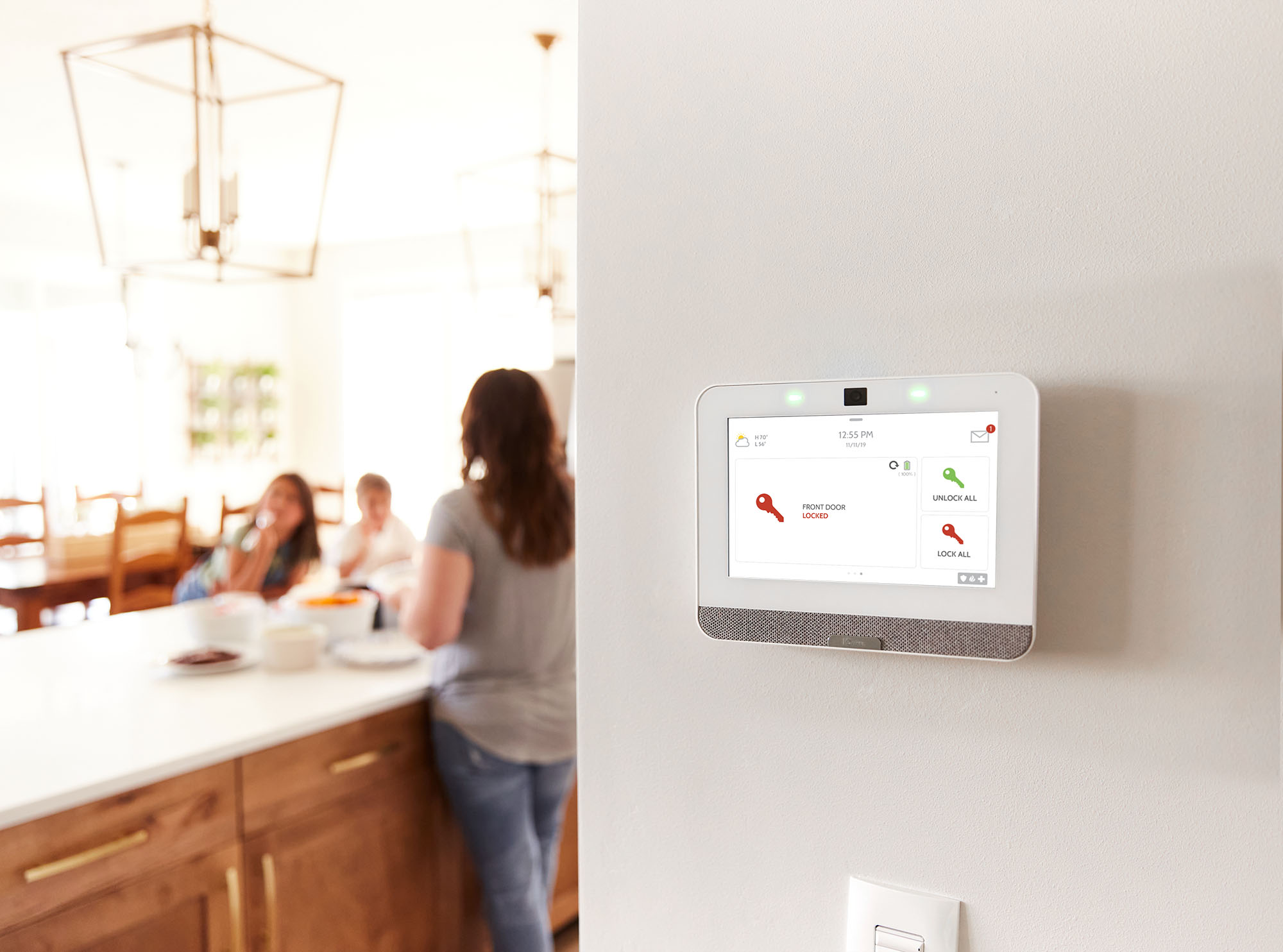 Family in kitchen with Guardian Protection security panel on wall