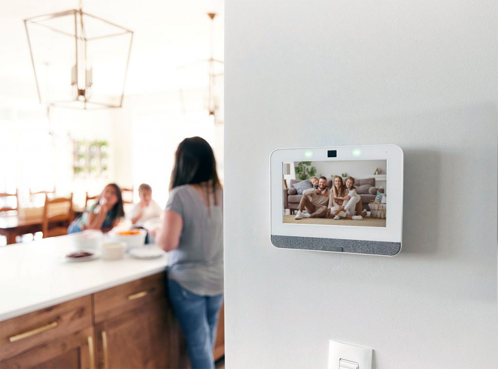 Mother talking to her children in the background with a focus on a personalized Guardian Protection security panel