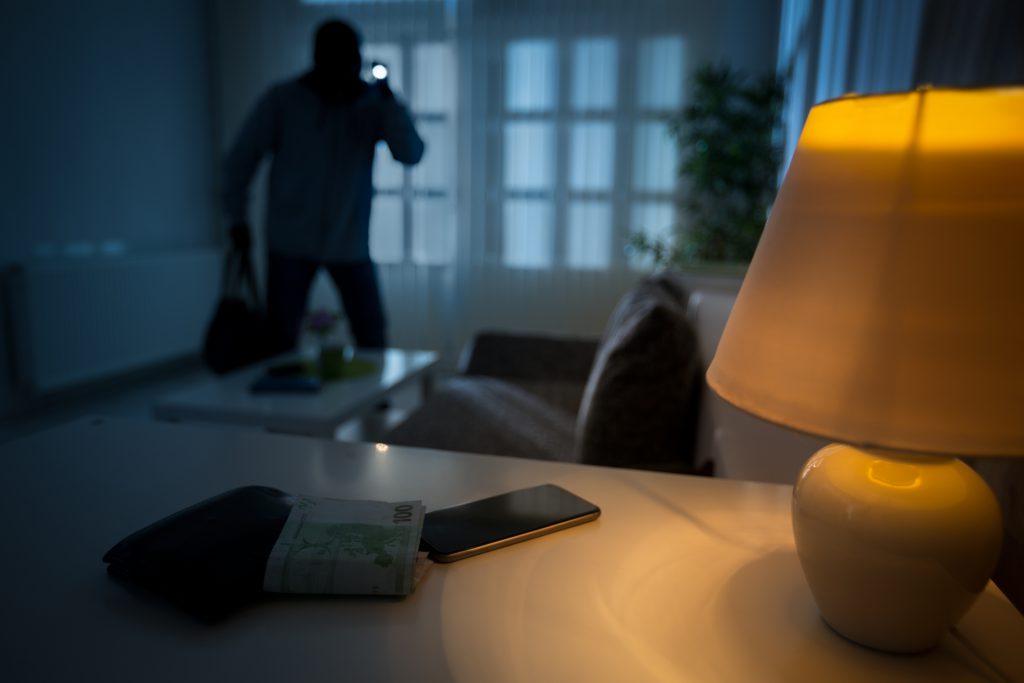 Burglar standing with flashlight in a home's living room