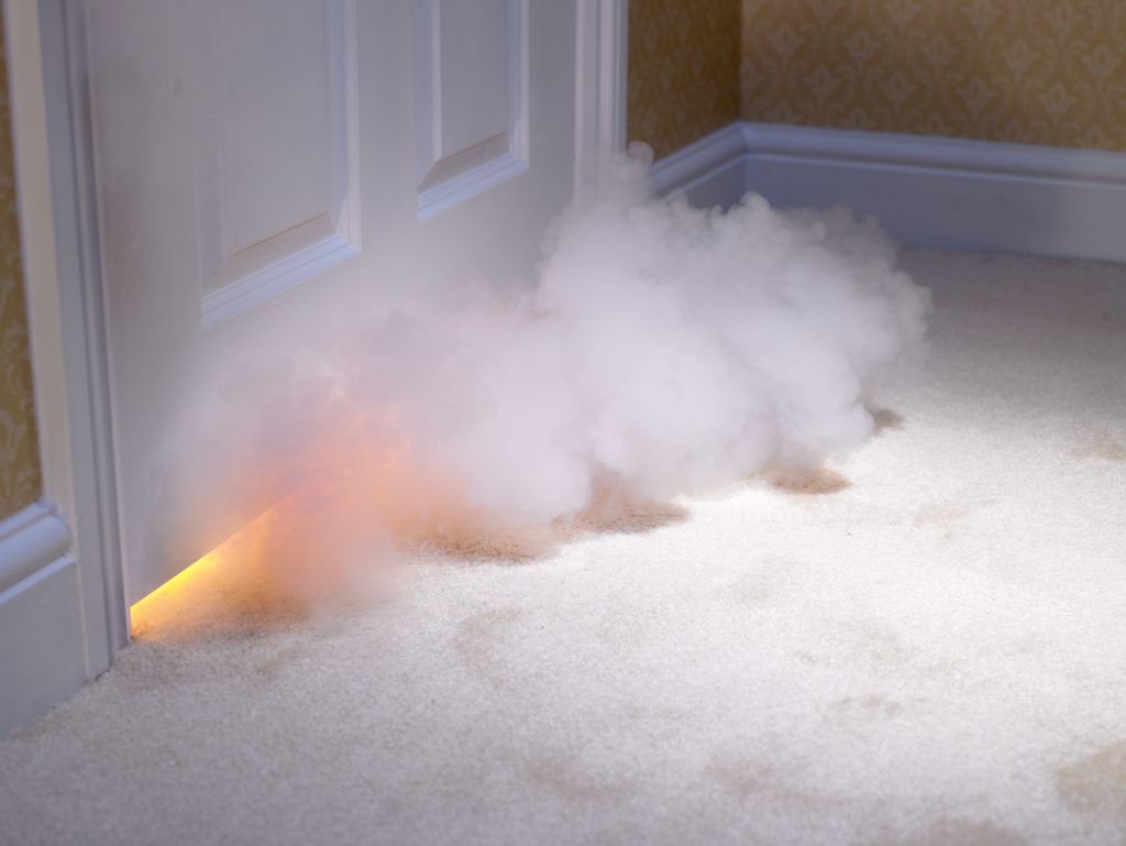 Smoke from a house fire coming up from under a door