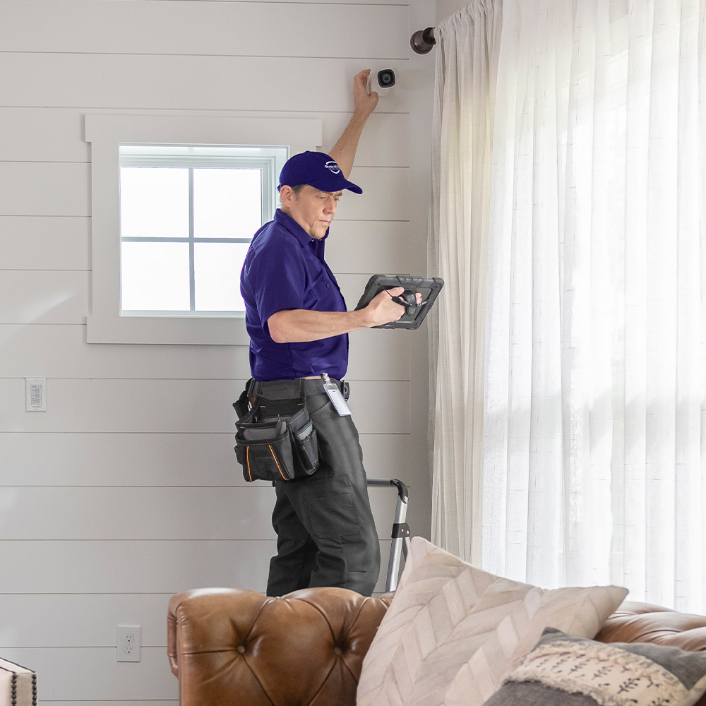 Guardian professional technician standing on a ladder to install an indoor home security camera