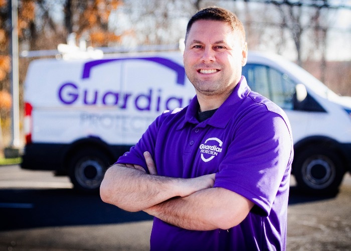 Guardian Protection professional installation technician standing in front of his Guardian van