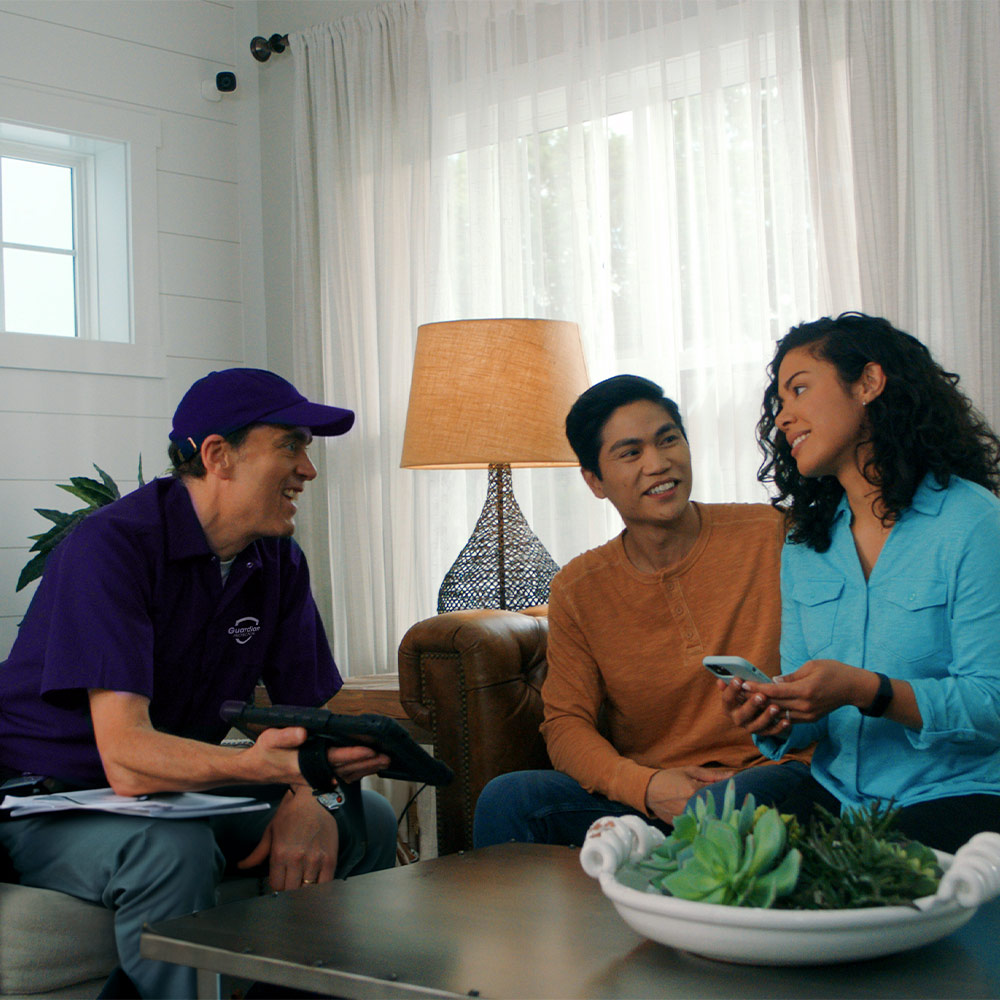 Guardian Protection home security expert with young couple in their home during personalized consultation.