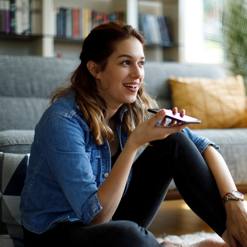 Woman using smartphone for indoor camera's two-way voice feature