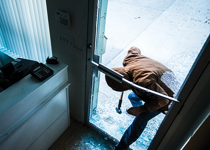 Burglar breaking into glass door of a business