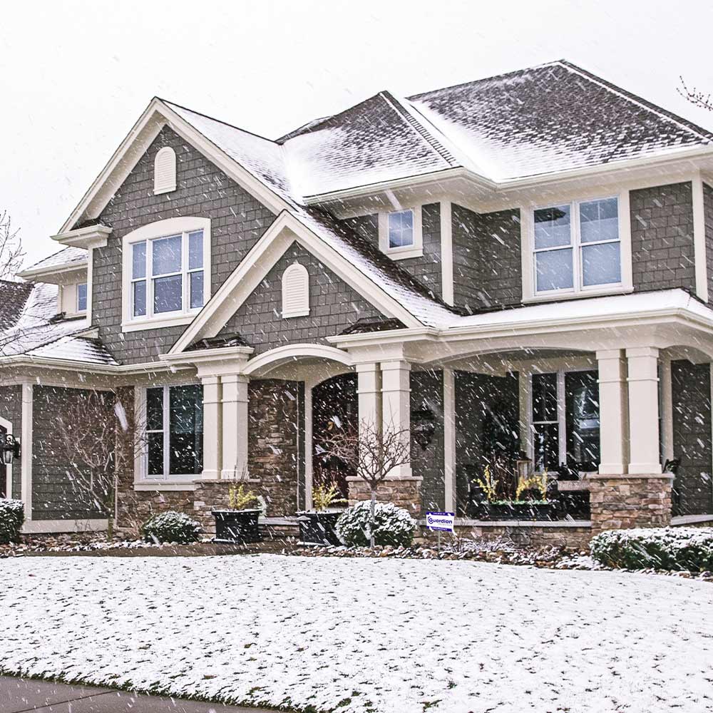 A snowy house with a Guardian Protection yard sign